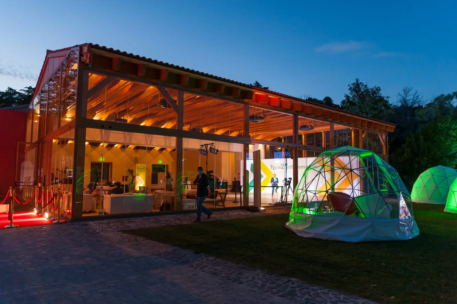 Pavilhão iluminado ao anoitecer num evento corporativo